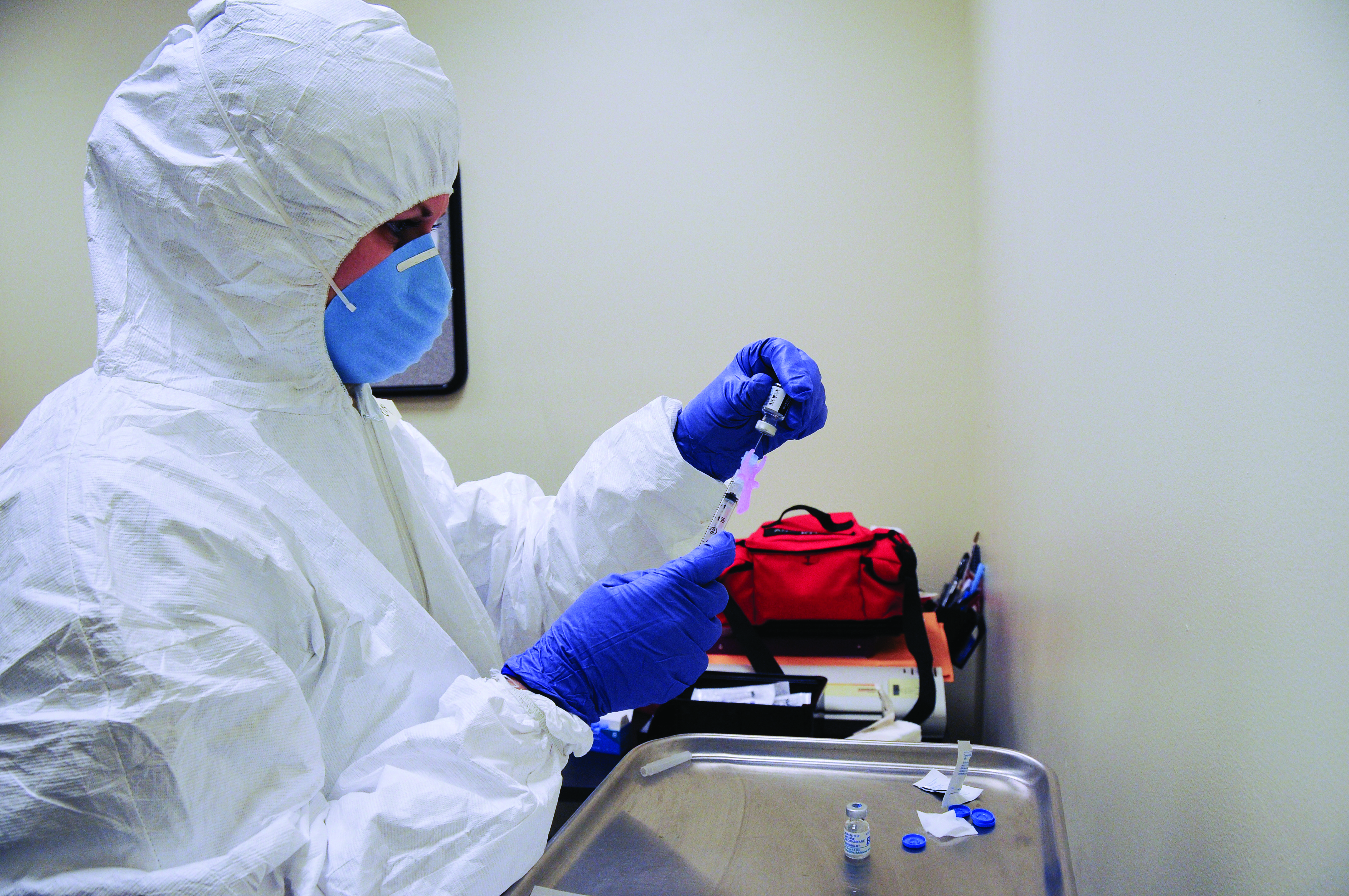 Image of individual in bio hazard suit, syringe in hand