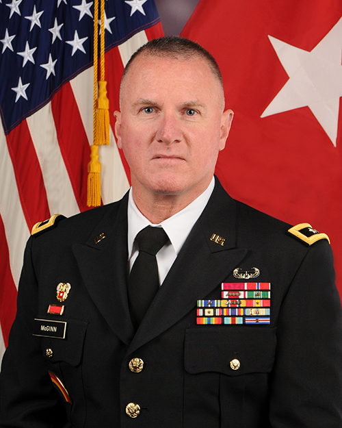 Image of uniformed member in front of flags. Image of uniformed member in front of flags.