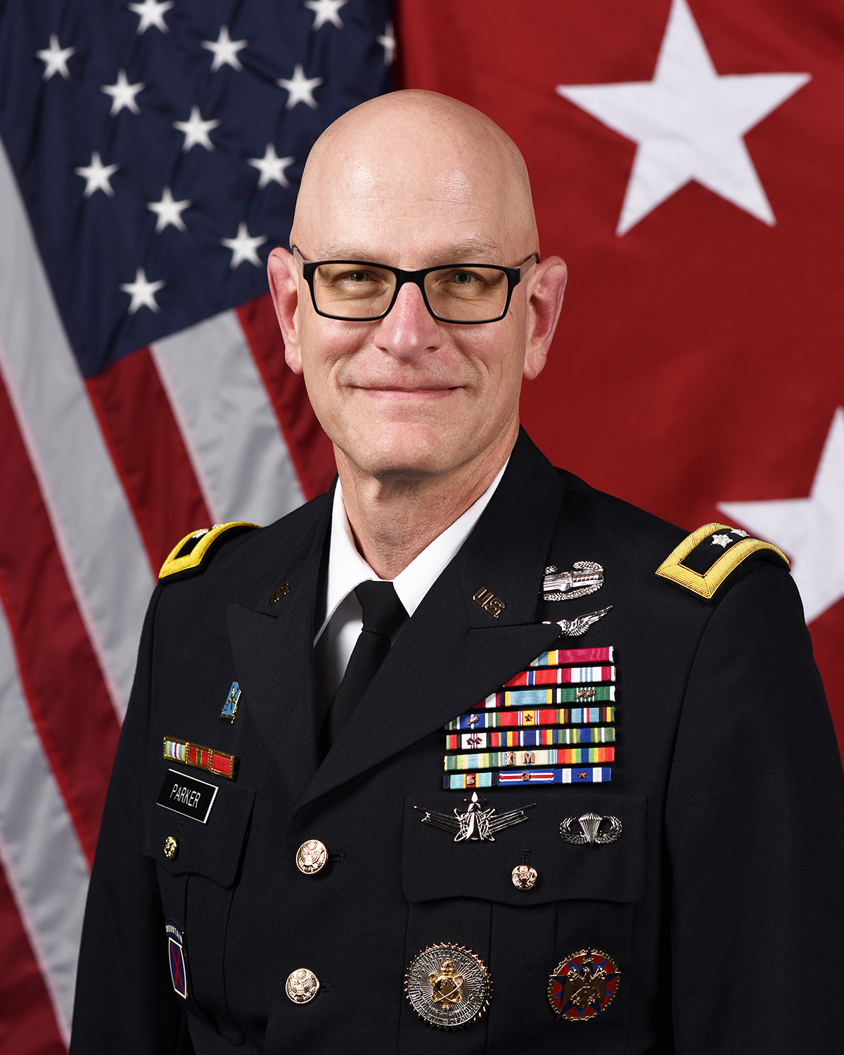 Image of uniformed member in front of flags.