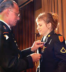 An Army general pins a medal on the uniform of Jessica Lynch during a formal ceremony.