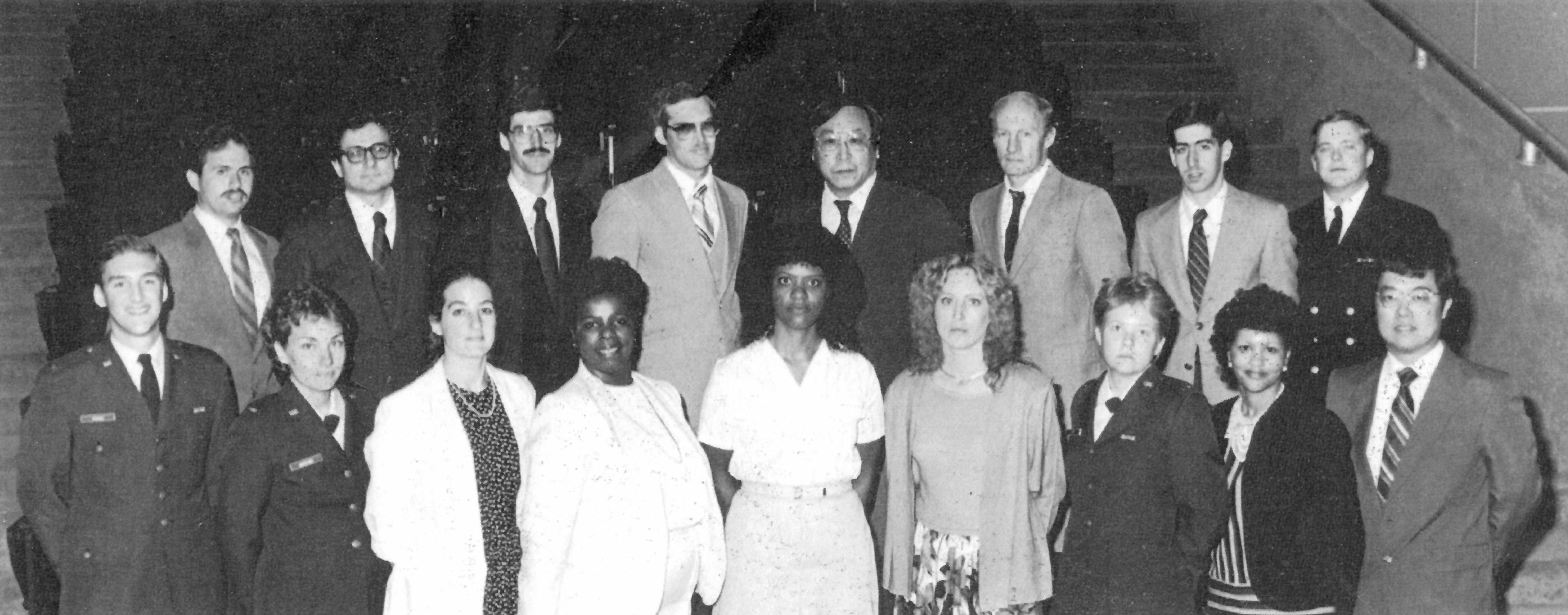 A black and white image of sevaral people standing together in two rows.