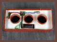The interior of a brick concealment device, showing three hollowed-out cylindrical compartments and wiring for housing electronic equipment.