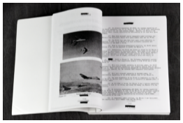 An open technical report showing a page with two black-and-white photographs of aircraft in flight opposite a page of heavily redacted text.