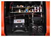 A detailed close-up of the internal electronics of a remotely operated vehicle, showing circuit boards, multi-colored wiring, and a safety warning label.
