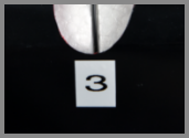 A close-up of a narrow vertical slit, marked as 3, cut into a car bumper to provide a concealed viewing port.