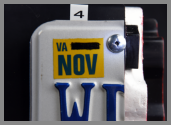 A close-up of a license plate holder, marked as 4, modified to create a concealment on a car bumper. The Virginia license plate sticker is visible.