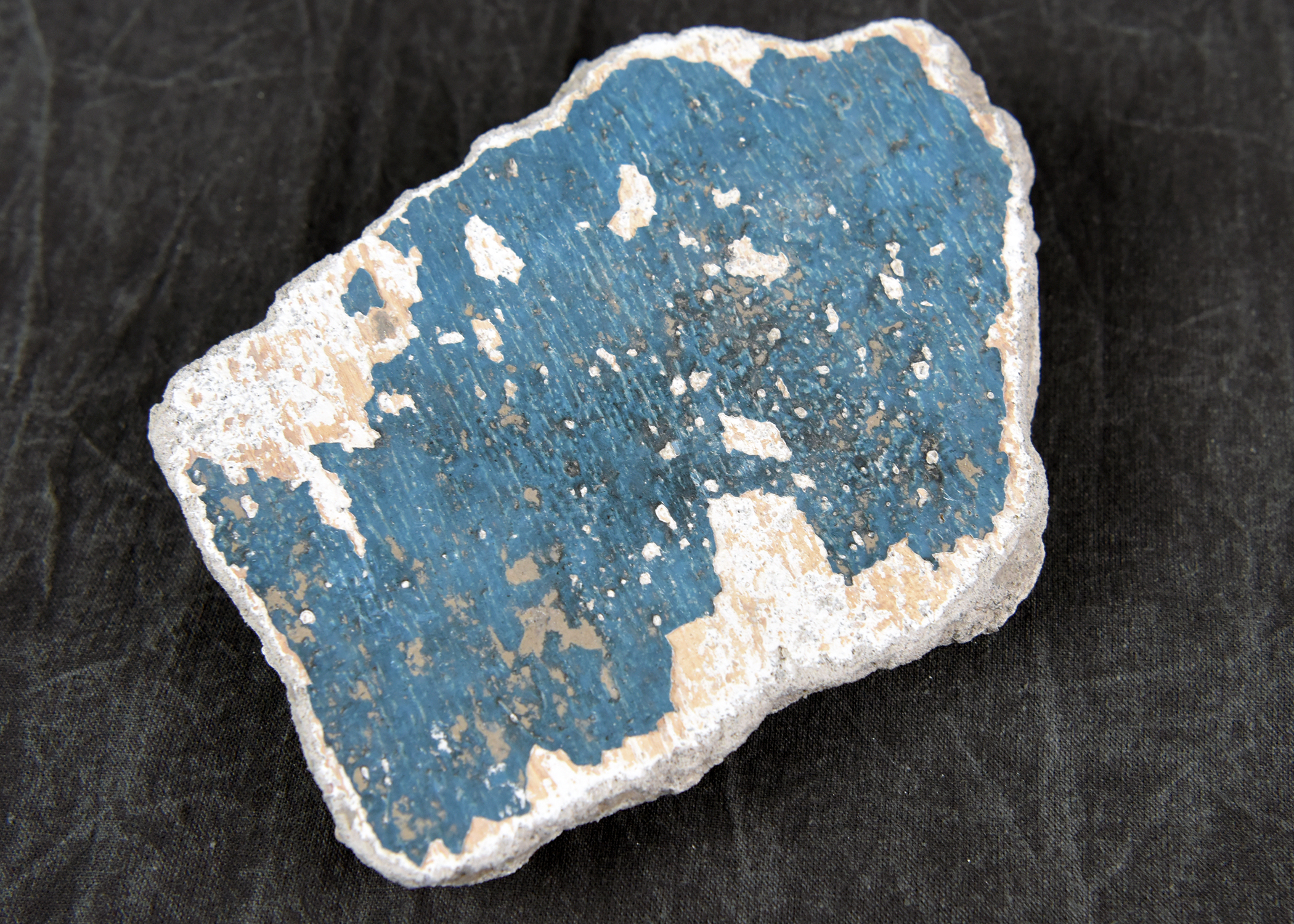 Image of a dark blue painted heavily damaged tile.