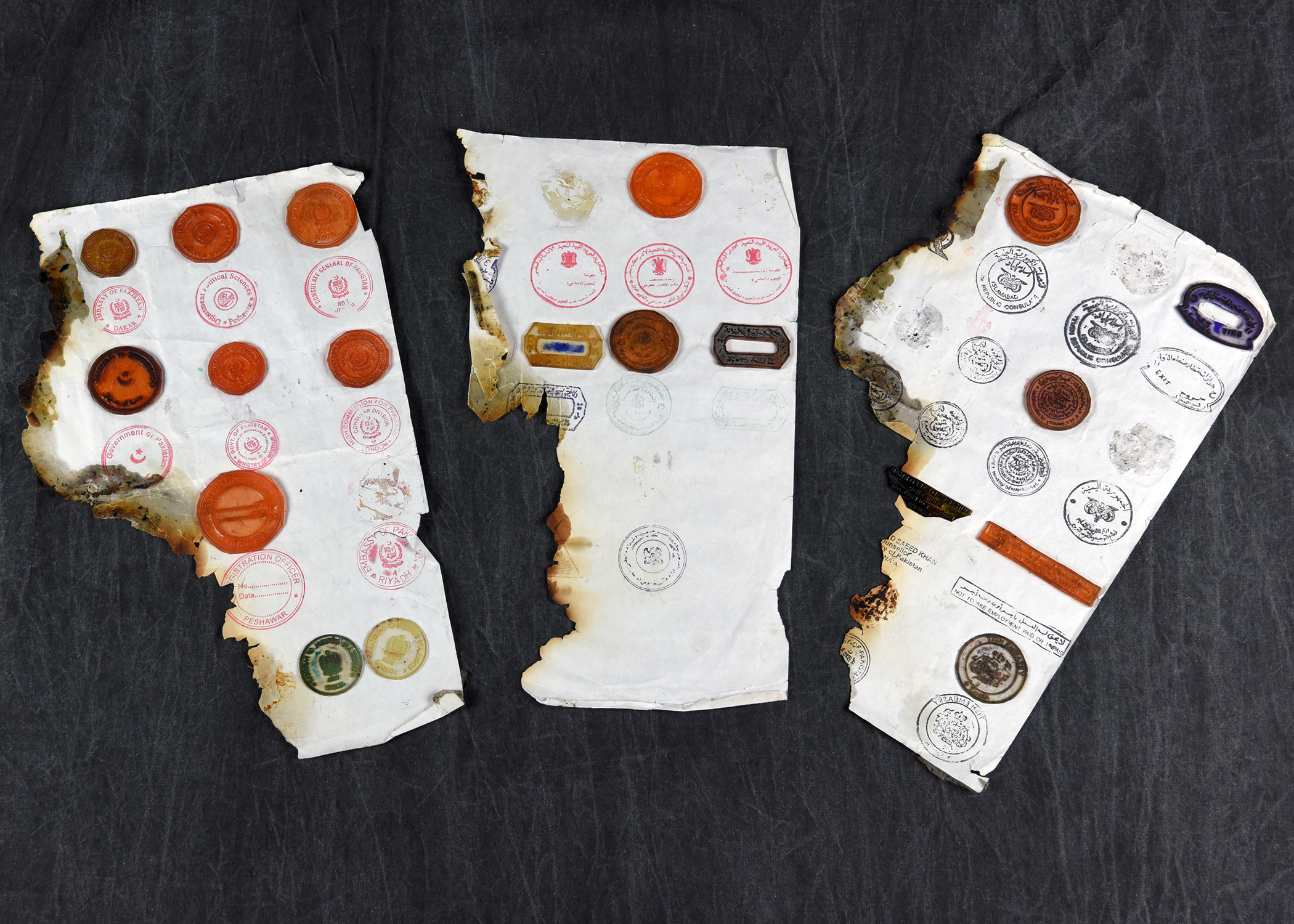 Image of 3 strips of damaged or burned paper with stamps on them.