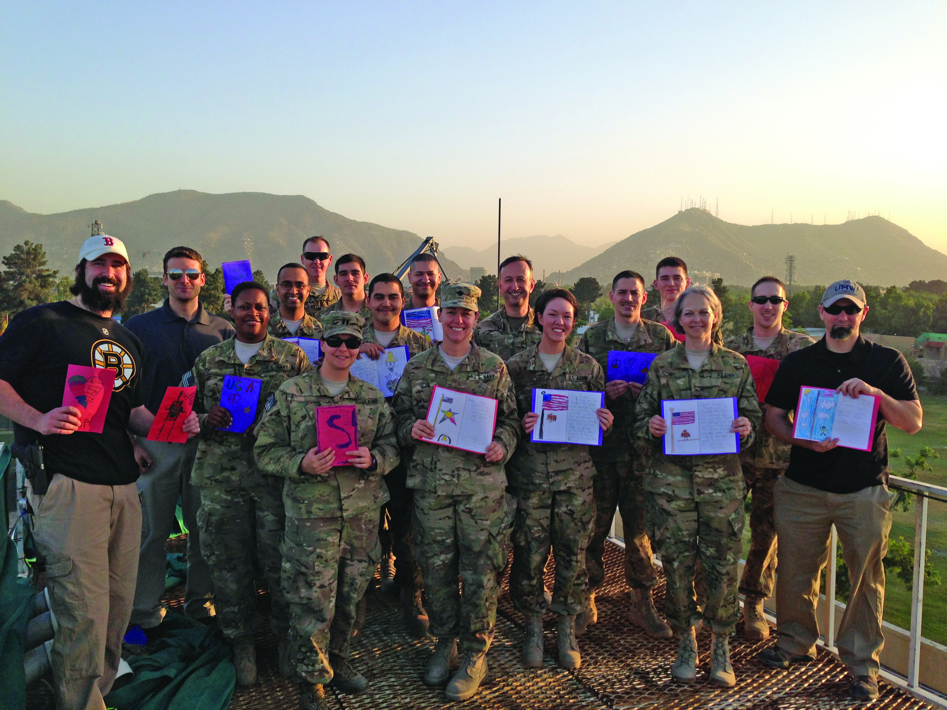 Image of several soldiers and personnel facing the camera holding up pieces of paper.