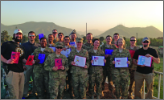 Image of several soldiers and personnel facing the camera holding up pieces of paper.